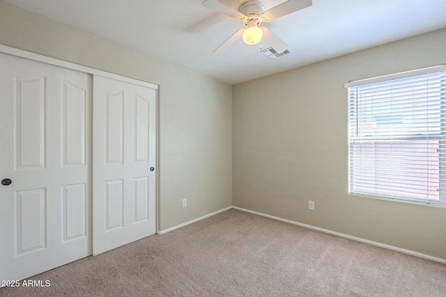 unfurnished bedroom with ceiling fan, light colored carpet, and a closet