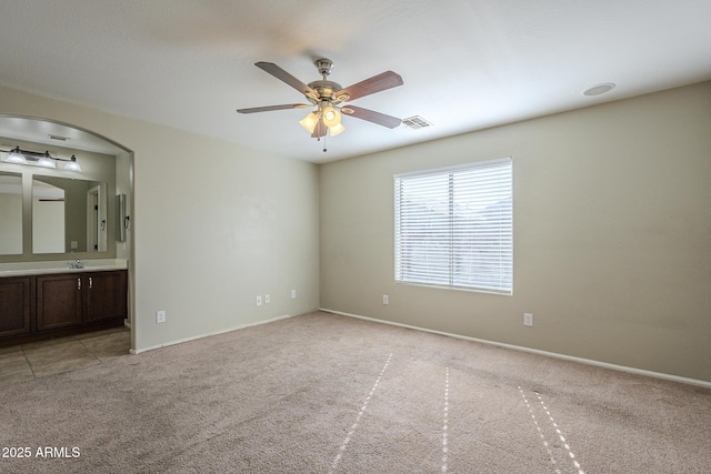 unfurnished room featuring light colored carpet, ceiling fan, and sink