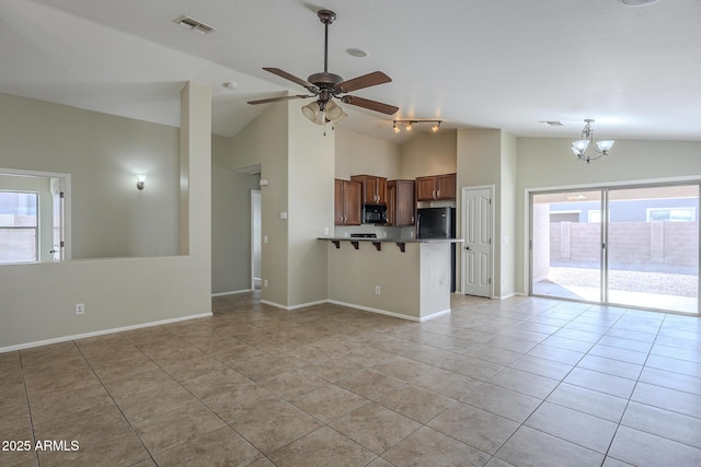 interior space with a kitchen bar, kitchen peninsula, light tile patterned floors, and vaulted ceiling