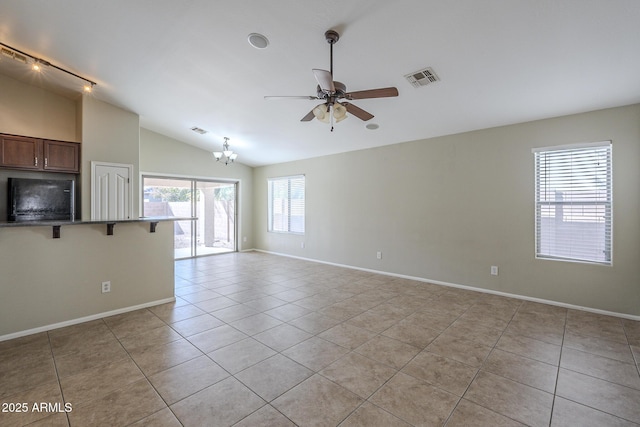 interior space with ceiling fan with notable chandelier, vaulted ceiling, and a healthy amount of sunlight