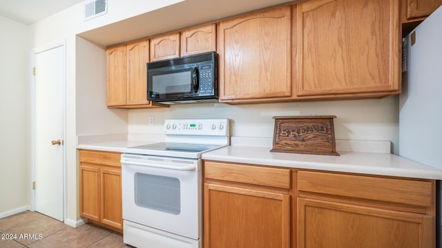 kitchen featuring light tile patterned flooring, light brown cabinets, and white range with electric stovetop