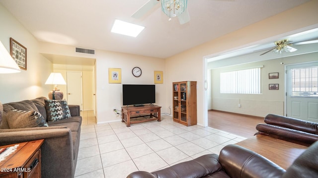 living room featuring light tile patterned floors, ceiling fan, and a skylight