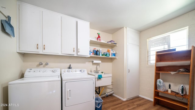 laundry area with independent washer and dryer, cabinets, sink, and hardwood / wood-style floors