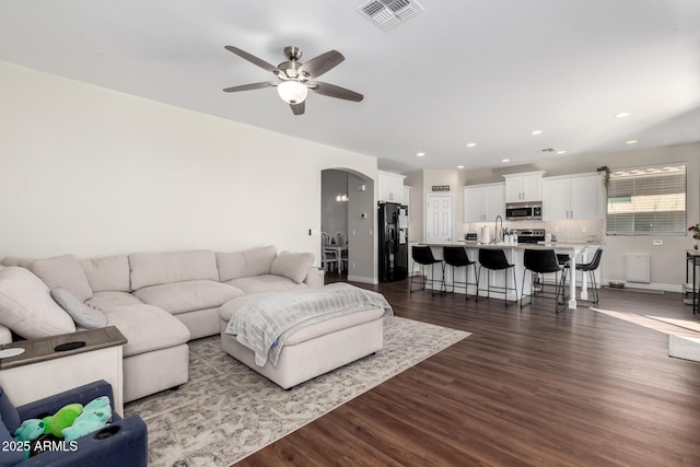 living room featuring arched walkways, ceiling fan, recessed lighting, visible vents, and dark wood finished floors