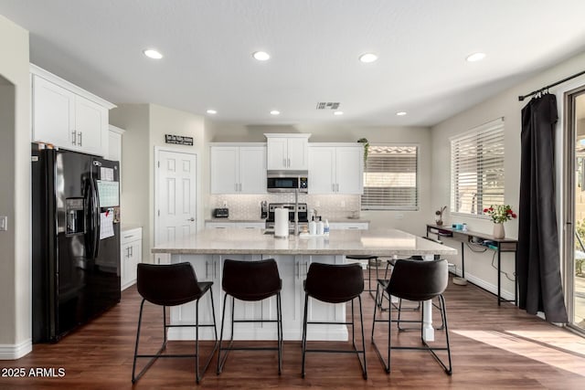 kitchen featuring white cabinets, a center island with sink, visible vents, and stainless steel appliances