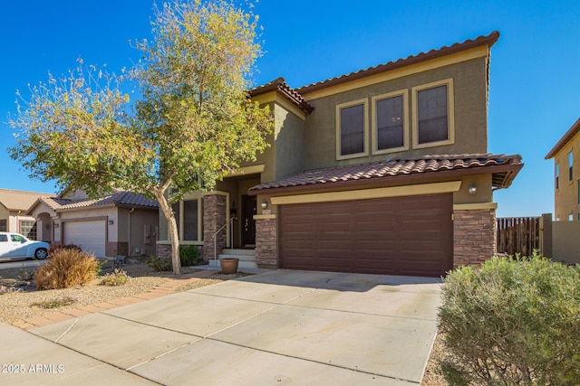 mediterranean / spanish house with concrete driveway, stone siding, a tile roof, an attached garage, and stucco siding