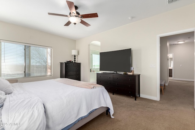 bedroom featuring arched walkways, light colored carpet, ceiling fan, and baseboards