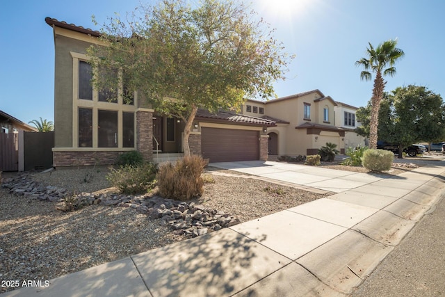 view of front of property with a garage, stone siding, concrete driveway, a tiled roof, and stucco siding