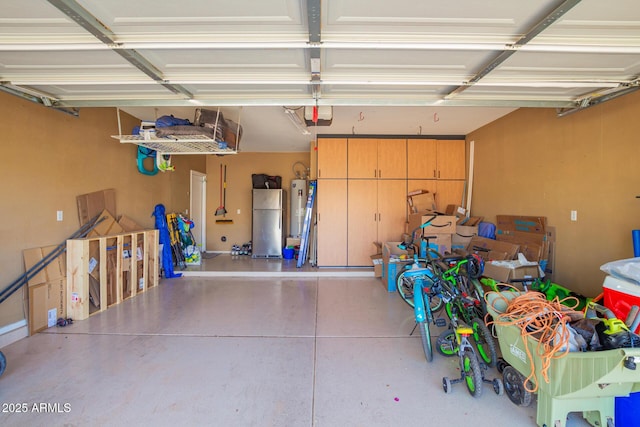 garage with a garage door opener, freestanding refrigerator, and electric water heater