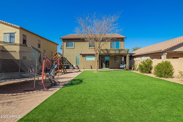 rear view of house with a patio, a fenced backyard, a trampoline, a playground, and stucco siding