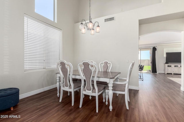 dining space featuring arched walkways, dark wood-style flooring, visible vents, and baseboards