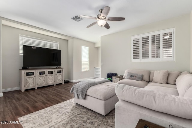 living area featuring a ceiling fan, dark wood finished floors, visible vents, and baseboards