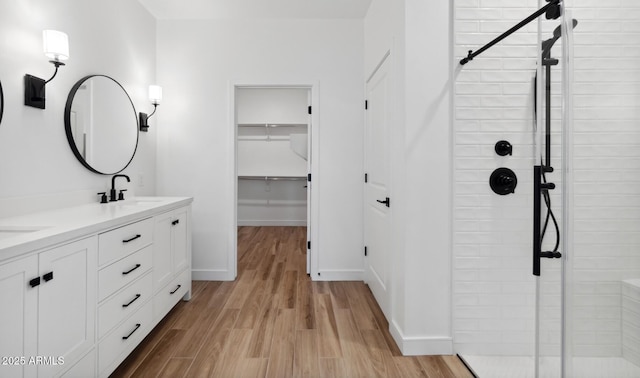 bathroom with vanity, tiled shower, and wood-type flooring