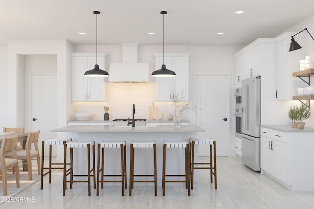 kitchen with white cabinets, hanging light fixtures, wall chimney range hood, and fridge