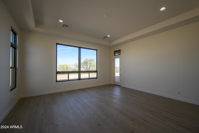 spare room featuring dark hardwood / wood-style floors and a raised ceiling