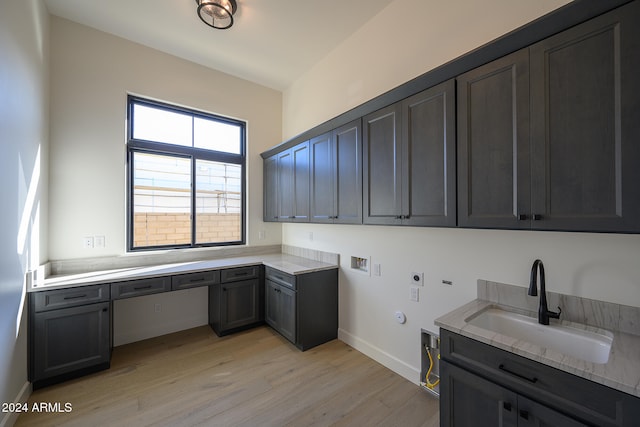 washroom featuring hookup for a washing machine, hookup for an electric dryer, sink, cabinets, and light hardwood / wood-style floors