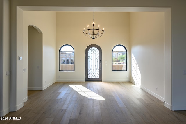 entryway featuring a notable chandelier, hardwood / wood-style flooring, and a high ceiling