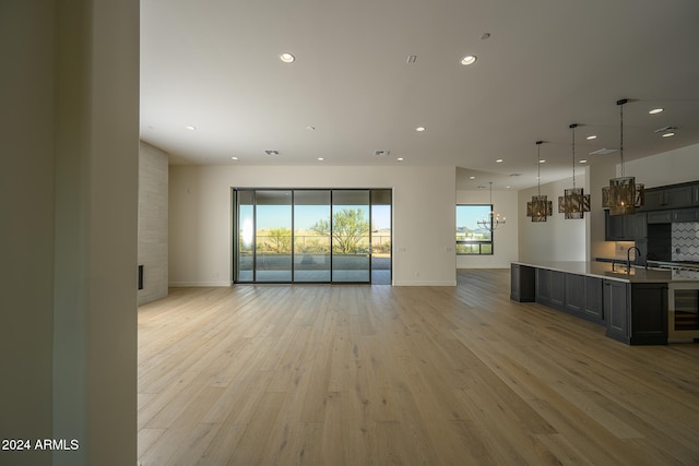 kitchen with decorative backsplash, decorative light fixtures, a chandelier, and light wood-type flooring