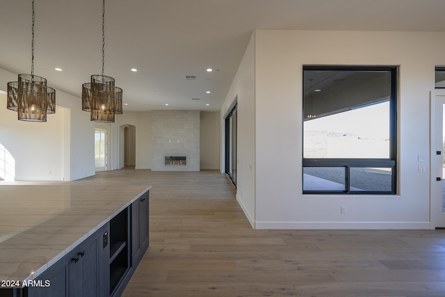 kitchen featuring a large fireplace, an inviting chandelier, pendant lighting, and wood-type flooring