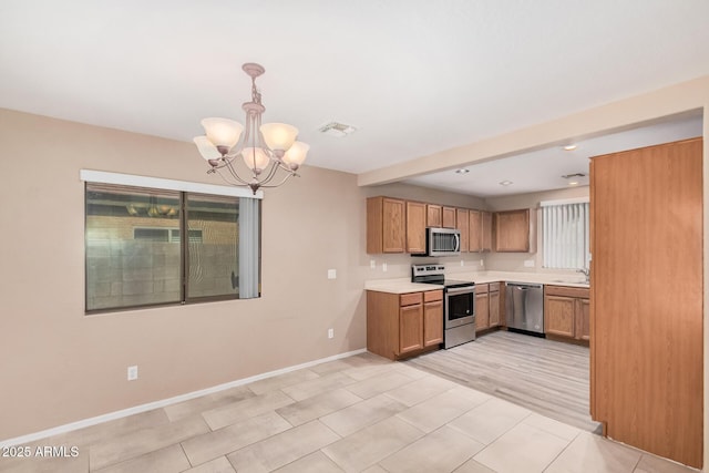 3719 W Carson Rd, Phoenix, AZ 85041 - kitchen with stainless steel appliances, a chandelier, light countertops, brown cabinets, and hanging light fixtures