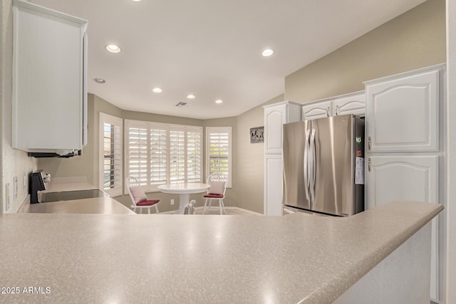 kitchen featuring lofted ceiling, stainless steel refrigerator, white cabinets, and range