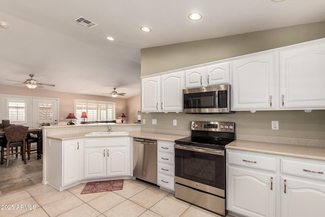 kitchen featuring stainless steel appliances, kitchen peninsula, sink, and white cabinets