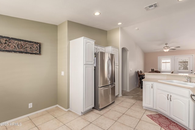 kitchen with white cabinetry, sink, light tile patterned floors, and stainless steel refrigerator