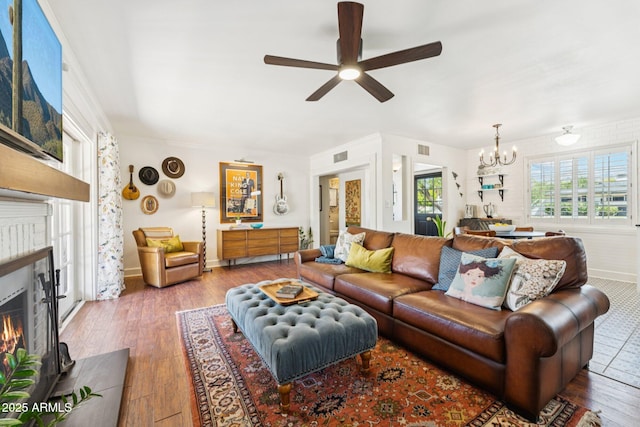 3201 E Colter St, Phoenix, AZ 85018 - living room with a warm lit fireplace, ceiling fan, a chandelier, and wood-type flooring