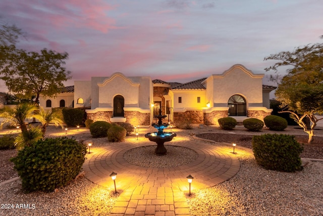 mediterranean / spanish-style house with stucco siding, a tiled roof, and stone siding