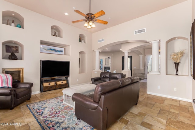 living room featuring ceiling fan, ornate columns, stone tile flooring, and visible vents