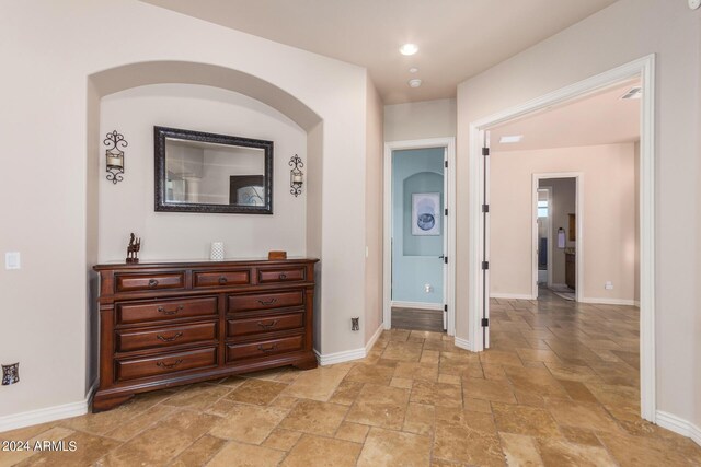 hallway featuring baseboards, stone tile floors, and recessed lighting