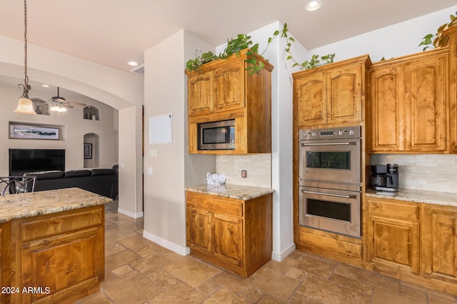 kitchen with stone tile flooring, recessed lighting, arched walkways, appliances with stainless steel finishes, and backsplash