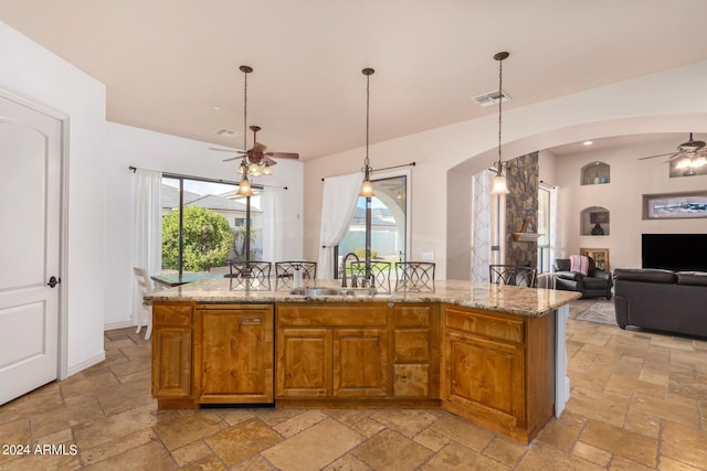 kitchen with stone tile floors, ceiling fan, arched walkways, and open floor plan