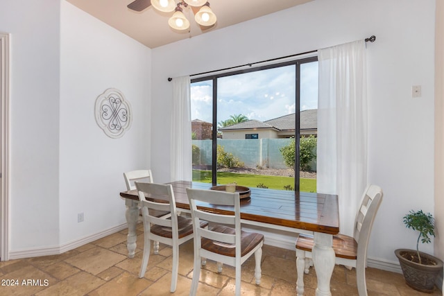 dining area with baseboards, ceiling fan, and stone tile flooring