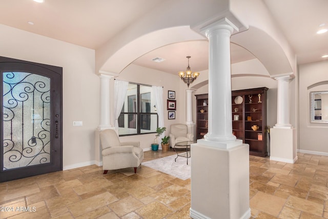 foyer featuring baseboards, decorative columns, visible vents, and stone tile flooring