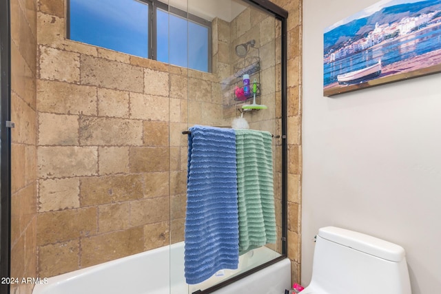 full bathroom with toilet and shower / bath combination with glass door