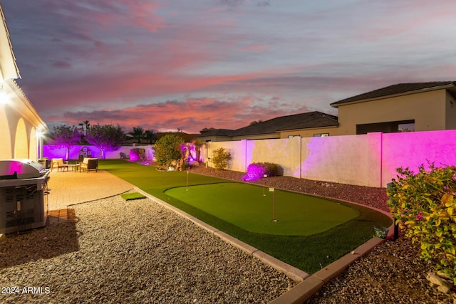 yard at dusk with a fenced backyard and a patio area
