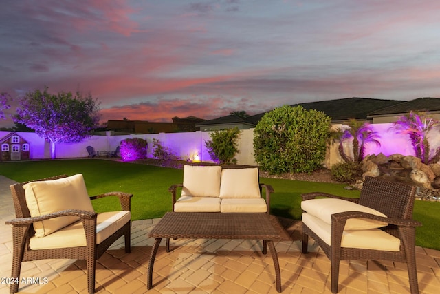 patio terrace at dusk featuring a yard, an outdoor living space, and a fenced backyard