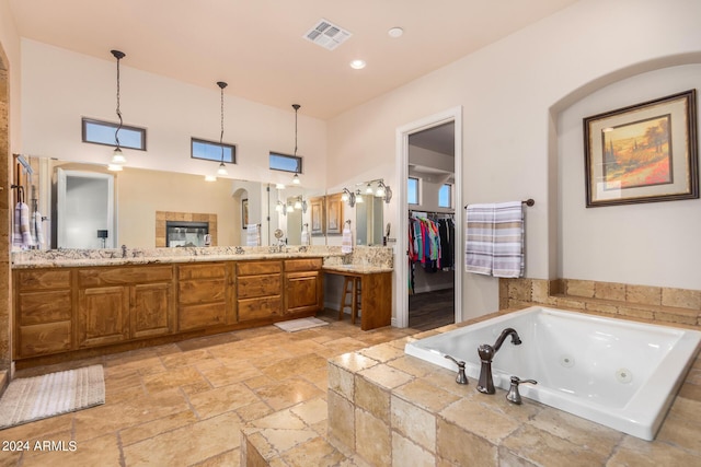 full bathroom featuring visible vents, double vanity, stone tile flooring, a jetted tub, and recessed lighting