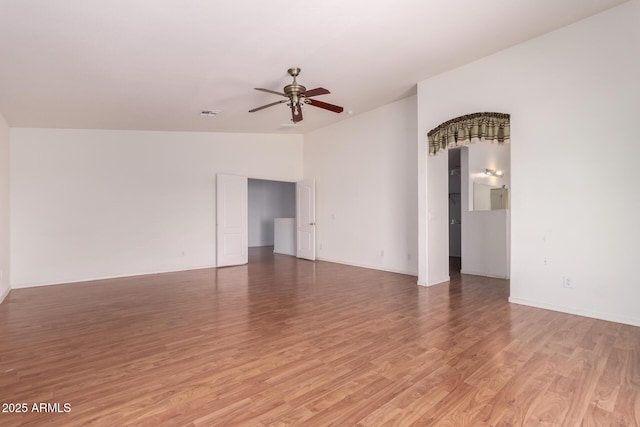 empty room featuring light wood-style floors, baseboards, ceiling fan, and vaulted ceiling