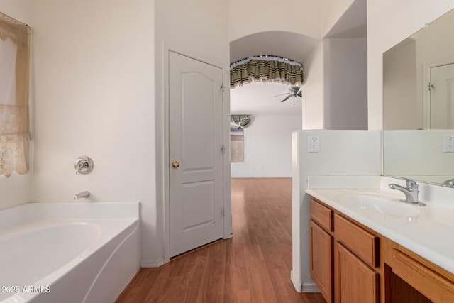 full bathroom featuring vanity, a garden tub, and wood finished floors