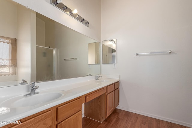 bathroom with a sink, double vanity, a shower stall, and wood finished floors