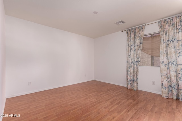 unfurnished room featuring baseboards, visible vents, and light wood finished floors