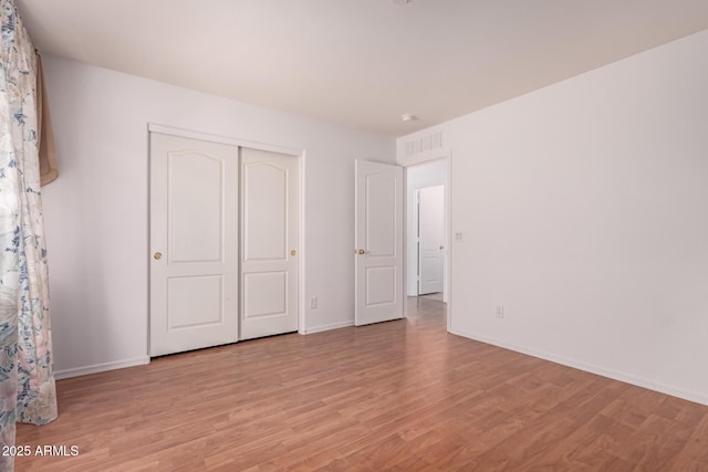 unfurnished bedroom featuring baseboards, light wood finished floors, and visible vents