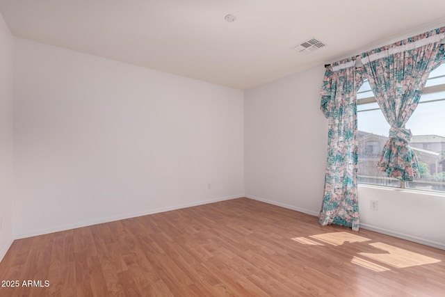 empty room featuring baseboards, light wood-type flooring, and visible vents