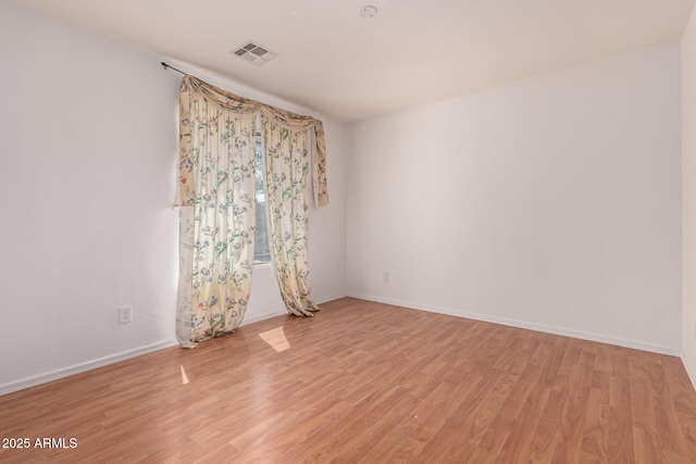 spare room with light wood-style floors, baseboards, and visible vents