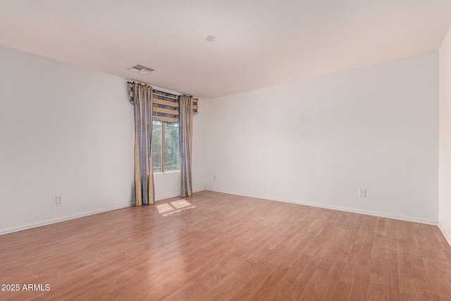 empty room with baseboards, visible vents, and light wood-style flooring