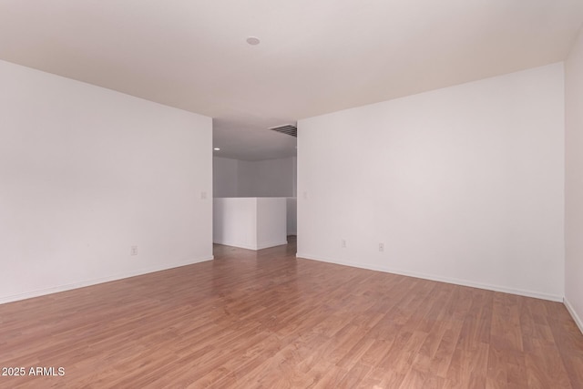 unfurnished room with visible vents, light wood finished floors, and baseboards