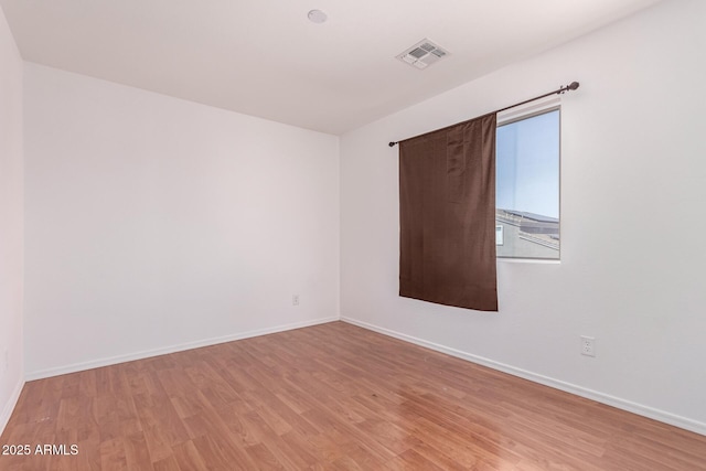 spare room with baseboards, visible vents, and light wood-style floors