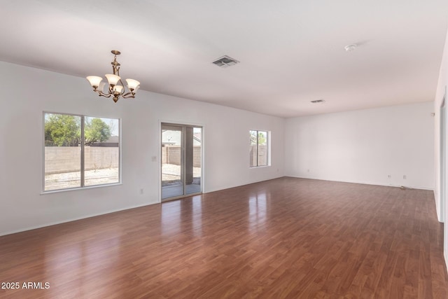 interior space with baseboards, an inviting chandelier, wood finished floors, and visible vents